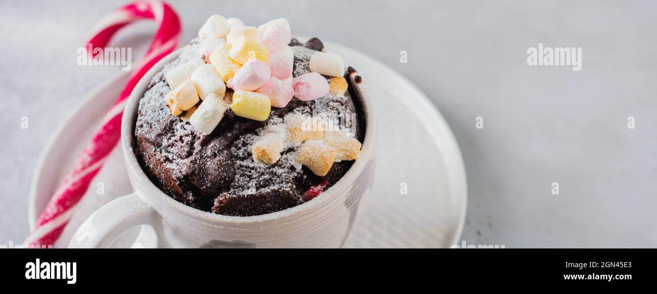 Neujahrs-Schokoladenkuchen in der Mikrowelle in Becher auf vintage grauen Hintergrund Textur gekocht. Draufsicht. Neujahrskarte. Stockfoto