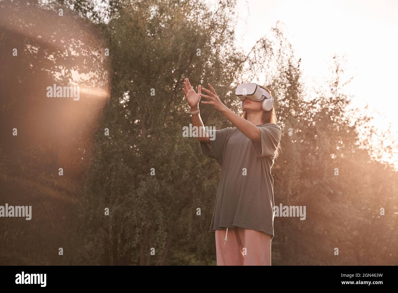 Ein Mädchen mit einer Virtual-Reality-Brille. Er reicht seine Hände an den Sonnenstrahl. Hochwertige Fotos Stockfoto