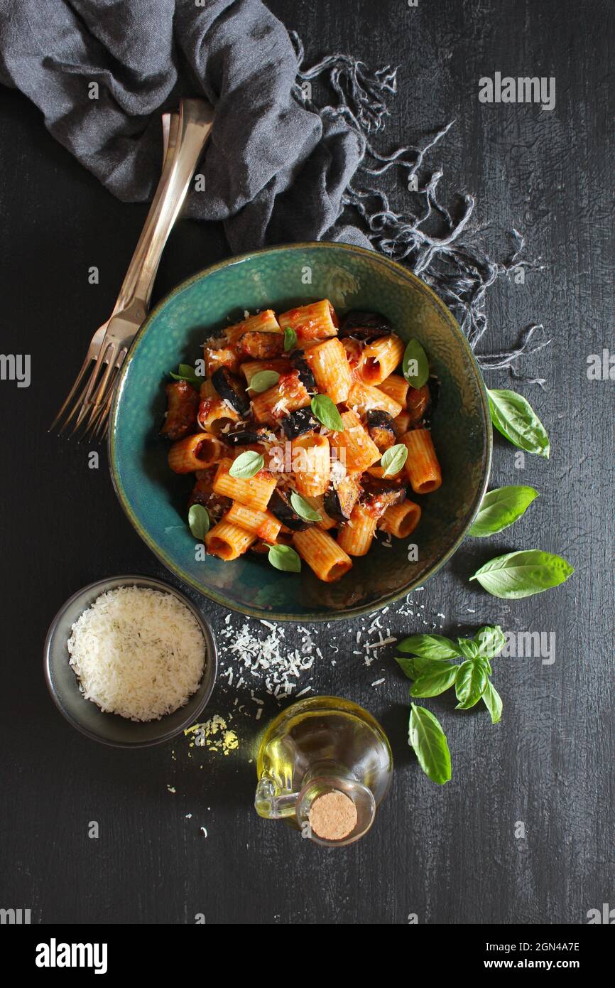 Pasta alla norma - Italienische Pasta mit Auberginen, Tomatensauce und Parmesan-Käseauf dunklem Tisch.Draufsicht mit Kopierraum. Stockfoto