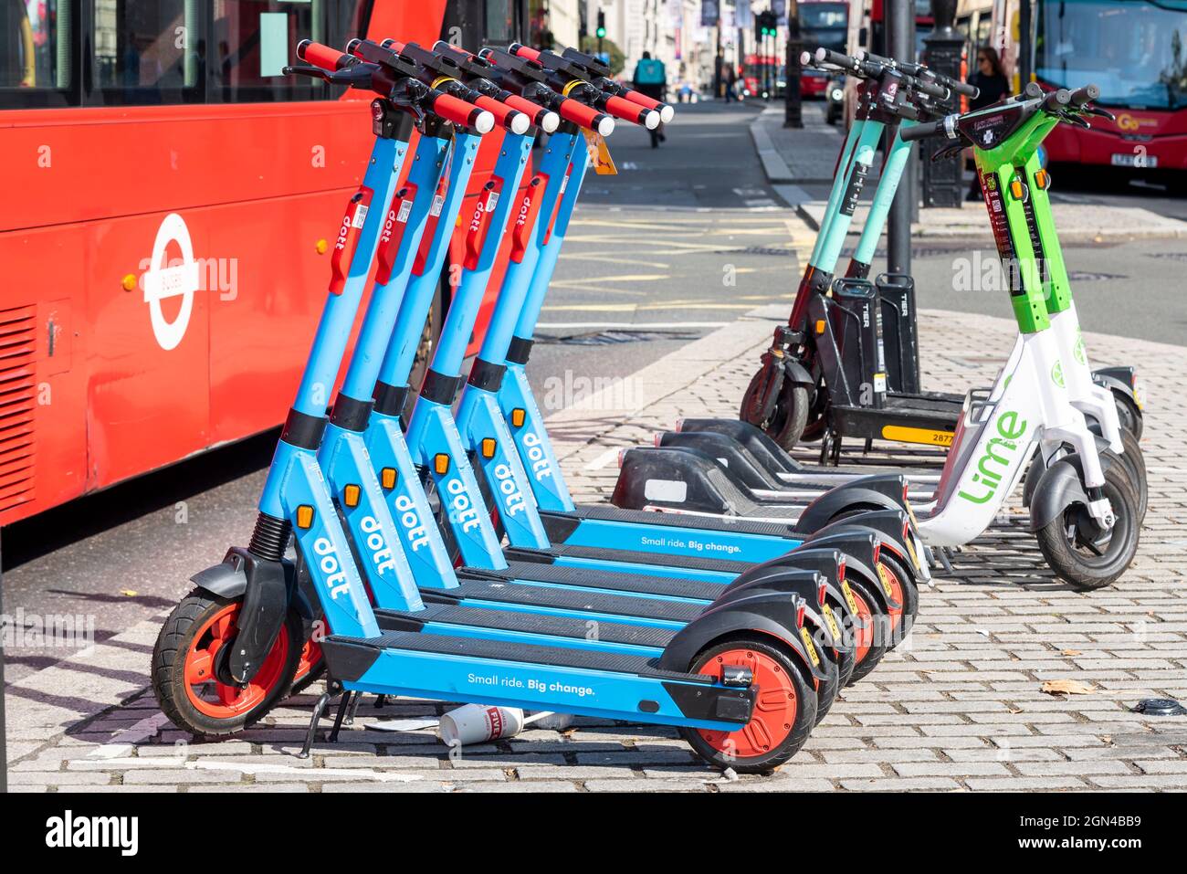 Lime und Dott e Scooter können in London, Großbritannien, mit Londoner Bussen gemietet werden. Elektroroller-Verleih Unternehmen, geparkt in belebten Stadtstraße Stockfoto