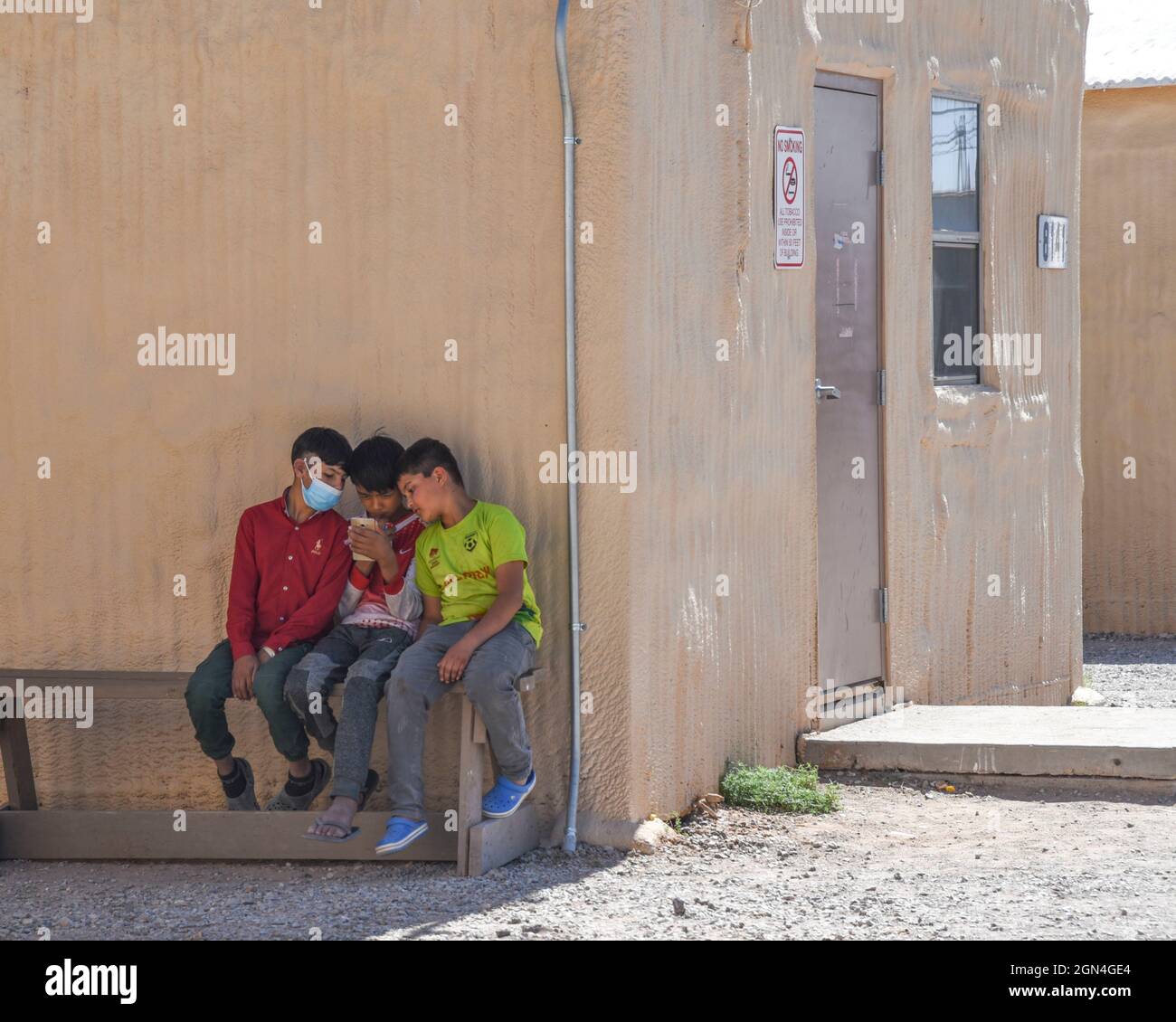 El Paso, Usa. September 2021. Afghanische Kinder spielen auf einem Handy in einem provisorischen Lager, das im Dona Ana-Komplex von Fort Bliss errichtet wurde, am 21. September 2021 in El Paso, Texas. Die Einrichtung bietet provisorischen Wohnraum, medizinische Vorsorgeuntersuchungen und allgemeine Unterstützung für afghanische Evakuierte. Kredit: Sgt. Briaira Tolbert/USA Army/Alamy Live News Stockfoto