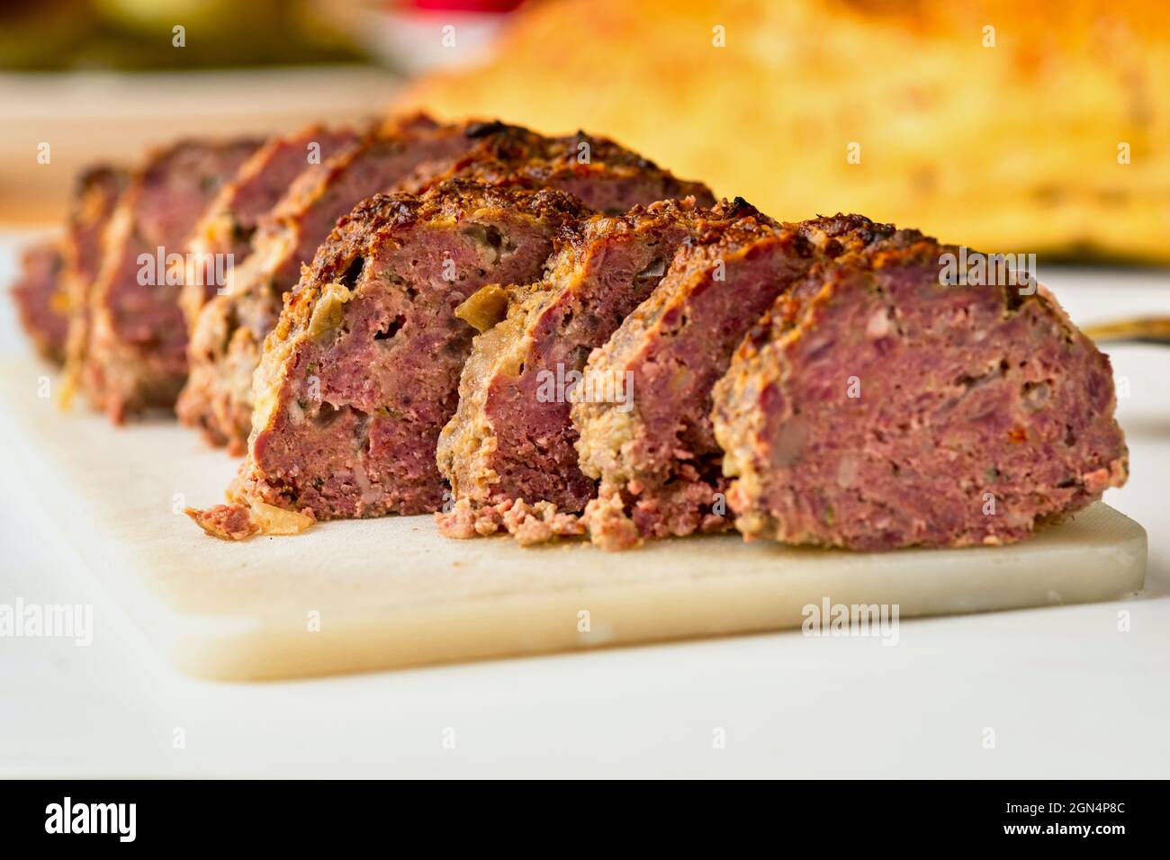 Gebackenes, in Scheiben geschnittenes Hackfleischl auf Küchenbrett, verschwommenes Brot auf dem Hintergrund. Stockfoto