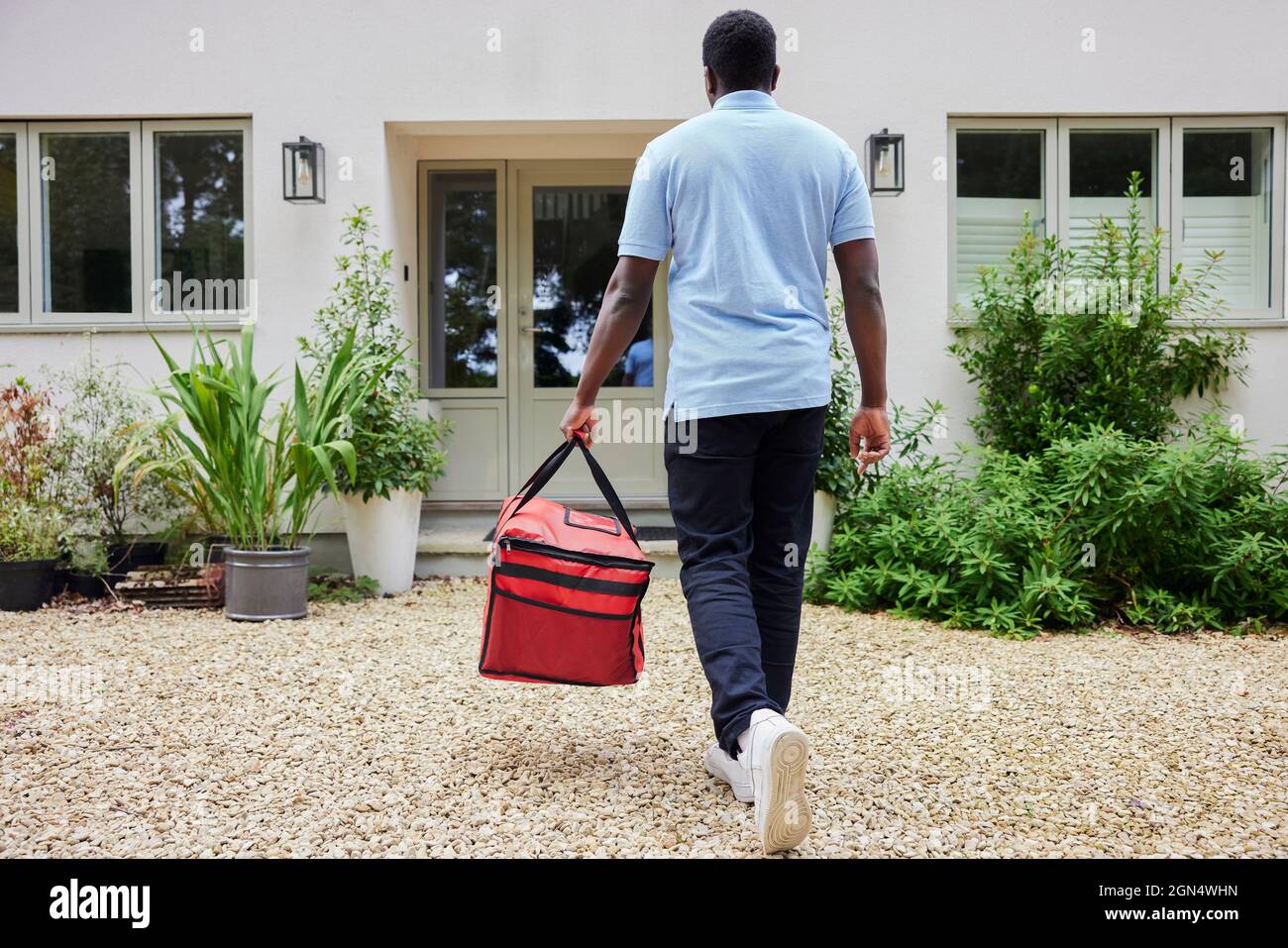 Rückansicht Des Gig Economy-Fahrers, Der Die Bestellung Von Lebensmitteln Im Online-Takeaway An Das Haus Liefert Stockfoto