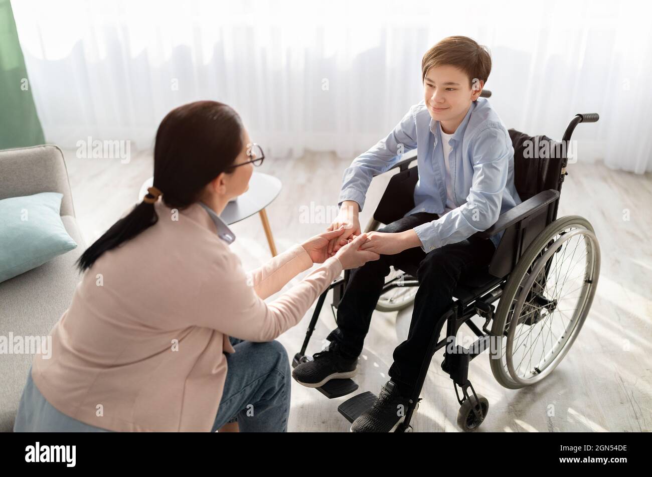 Psychotherapieberatung. Berater, der behinderten Jugendlichen im Rollstuhl im Büro Hilfe und Unterstützung anbietet Stockfoto