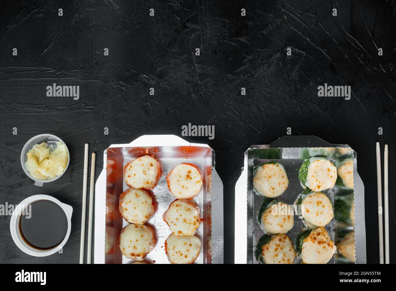 Set Sushi-Rollen im Lieferkarton-Set, auf schwarzem Stein-Hintergrund, Draufsicht flach liegend, mit Texteraum und Platz für Text Stockfoto