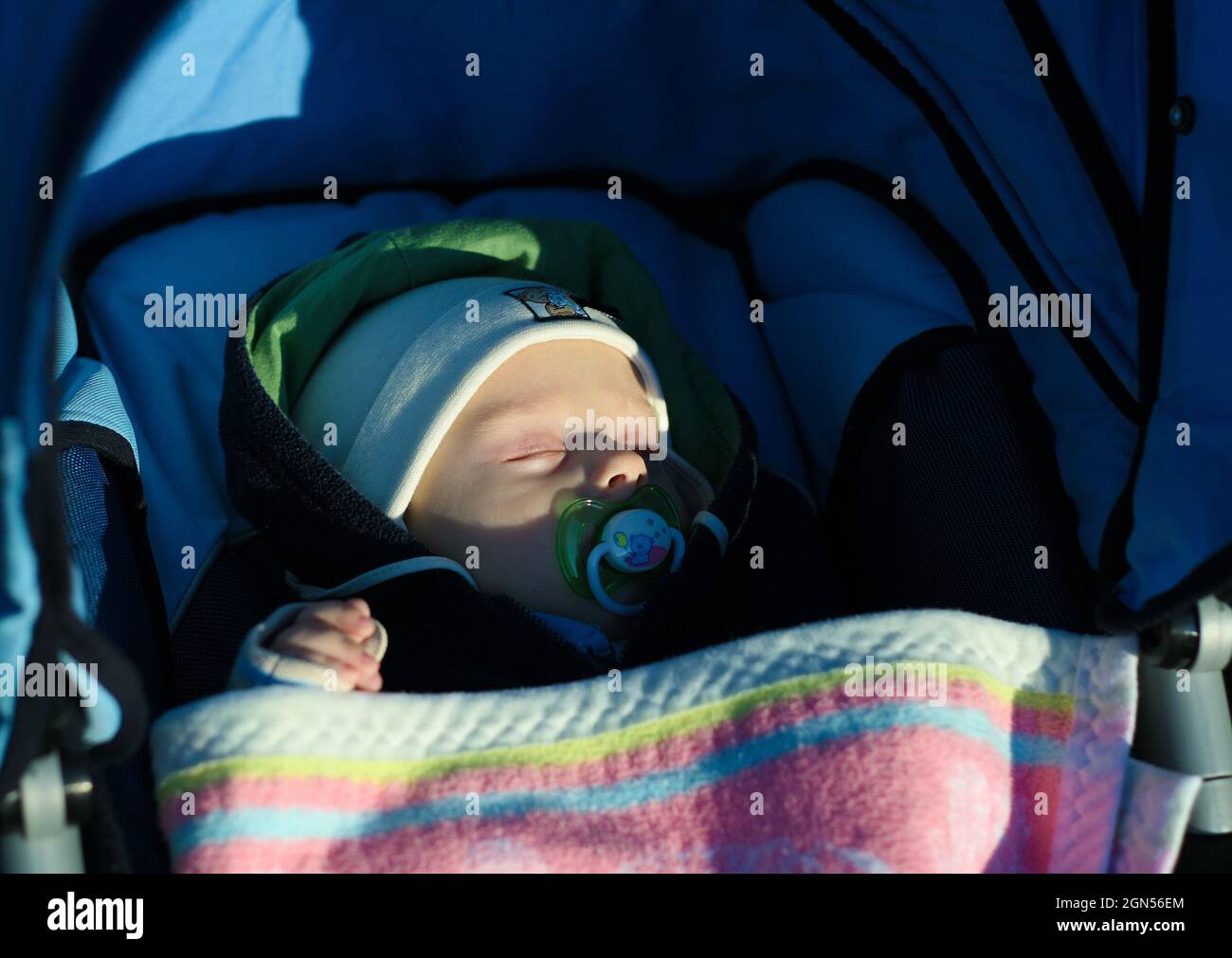 Fünf Monate alten Jungen schlafen mit Schnuller im Kinderwagen auf dem Weg Stockfoto