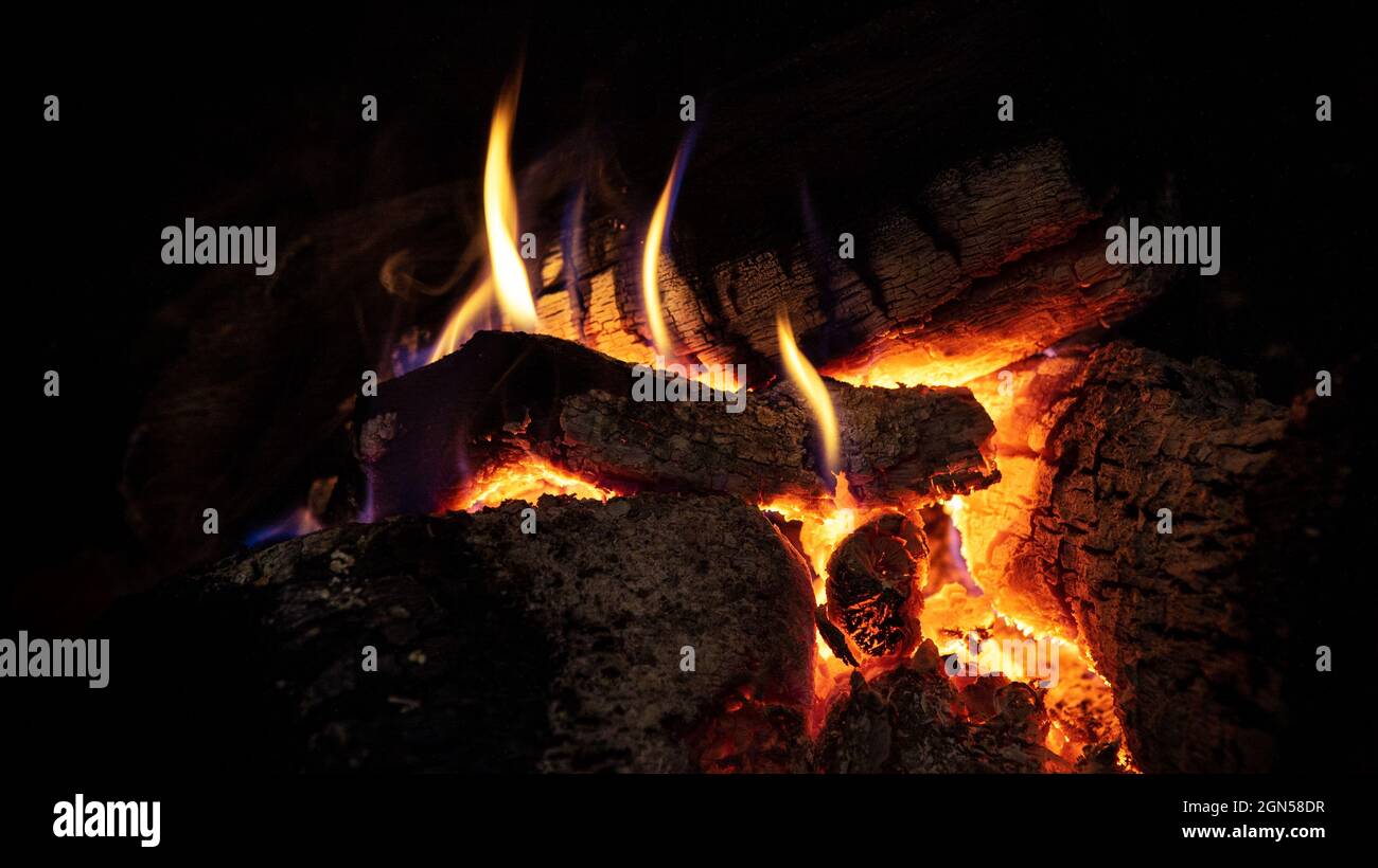 Heisses brüllendes Feuer und rote Kohlen in einem Kamin. Brennendes Holz in Schornstein und warme Atmosphäre im Winter. Helle Flamme des Feuers brennt Stockfoto