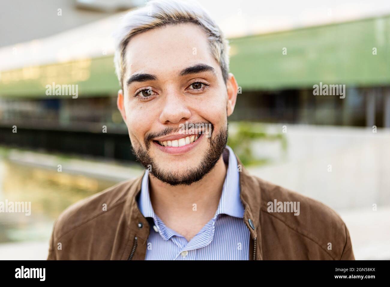 Junger hispanischer Mann lächelt draußen vor der Kamera Stockfoto