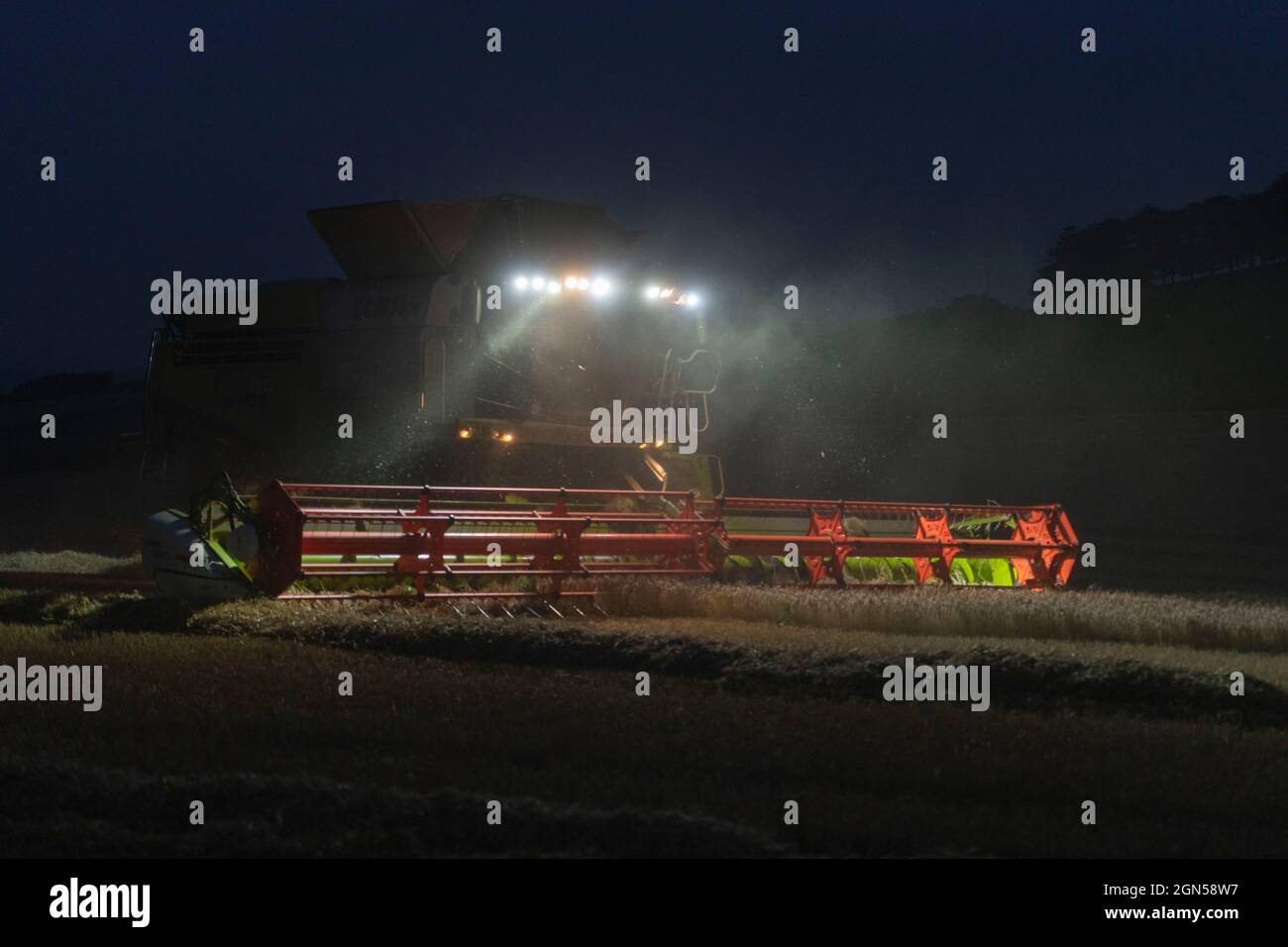 Ein Mähdrescher, der nach Einbruch der Dunkelheit in einem Gerstenfeld in Aberdeenshire eingesetzt wird Stockfoto