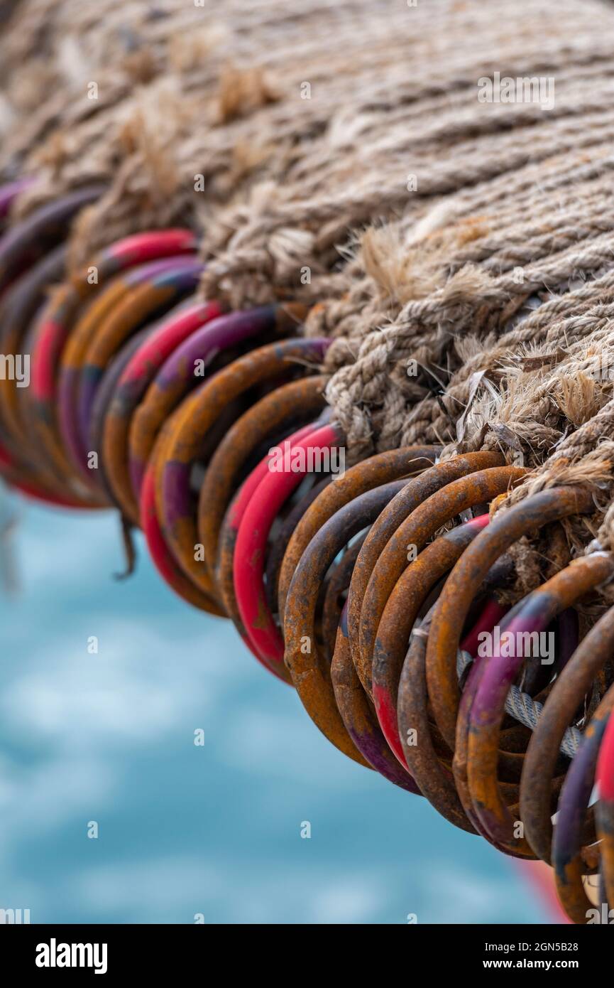 Bunte Ringe und Reifen am Rand eines griechischen Fischernetzes bilden ein abstraktes Muster, das für einen Hintergrund oder Hintergrund geeignet ist. Muster, die durch Netz gebildet werden Stockfoto
