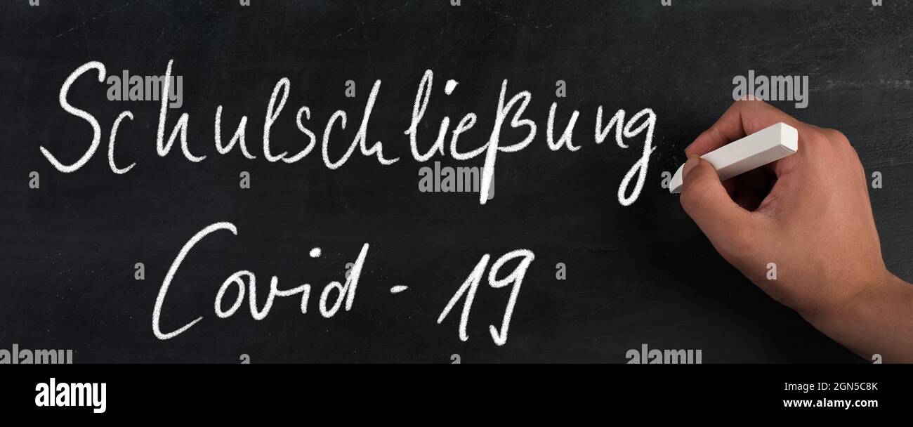 Schule geschlossen, weil Covid-19 in deutscher Sprache auf einer Tafel steht Stockfoto
