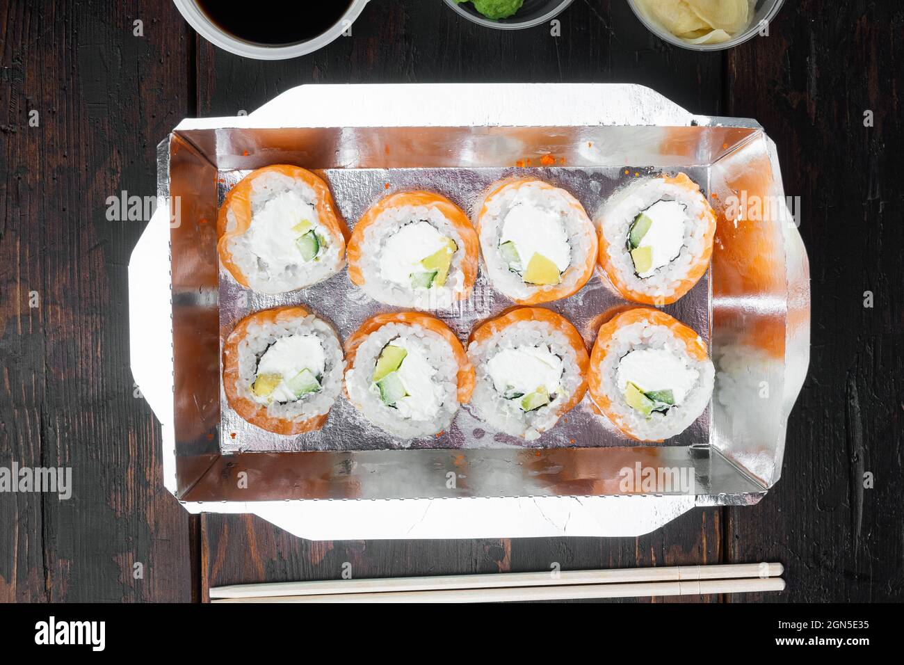 Sushi-Rollen im Container zum Mitnehmen, auf altem dunklen Holztischhintergrund, Draufsicht flach liegend Stockfoto
