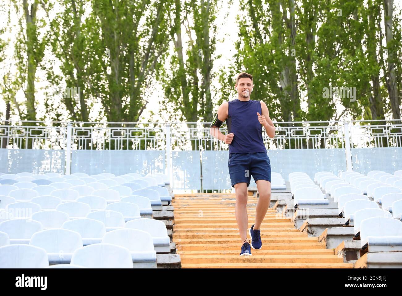 Sportlicher junger Mann, der unten im Stadion läuft Stockfoto