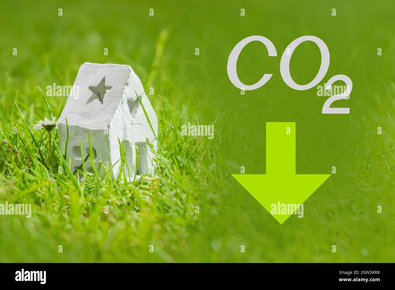 Reduzierung der Kohlendioxidemissionen, Begrenzung der globalen Erwärmung und Konzept des Klimawandels. Weißes Haus, CO2-Schild und grüner Pfeil nach unten Stockfoto