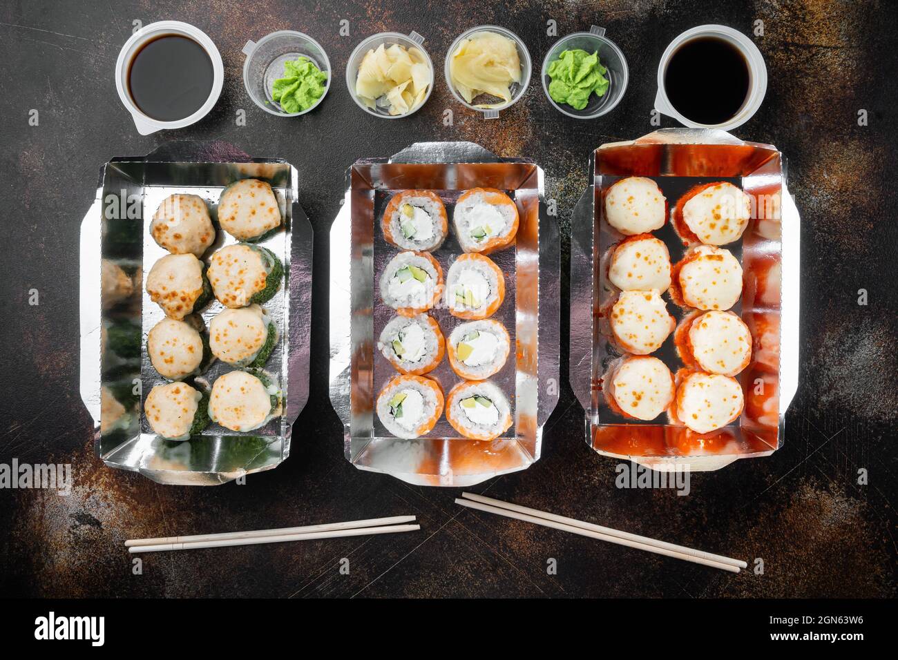 Japanisches Speisekonzept. Catering, verschiedene Arten von Sushi philadelphia Brötchen und gebackene Garnelen Brötchen Set, auf alten dunklen rustikalen Hintergrund, Draufsicht flach Lay Stockfoto