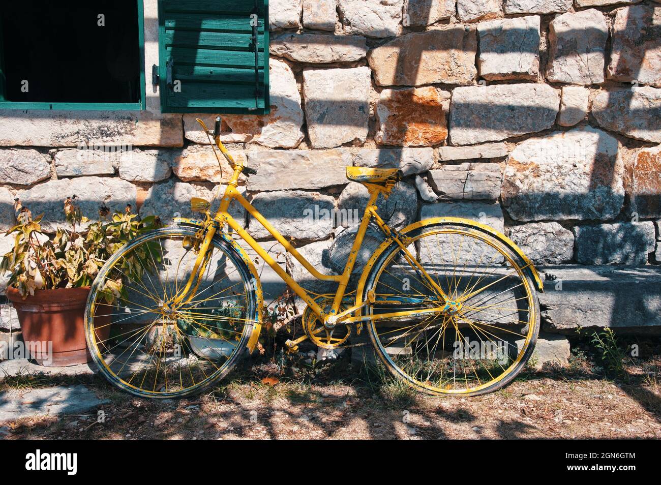 Altes Retro-Fahrrad, das sich an der Steinmauer lehnt Stockfoto