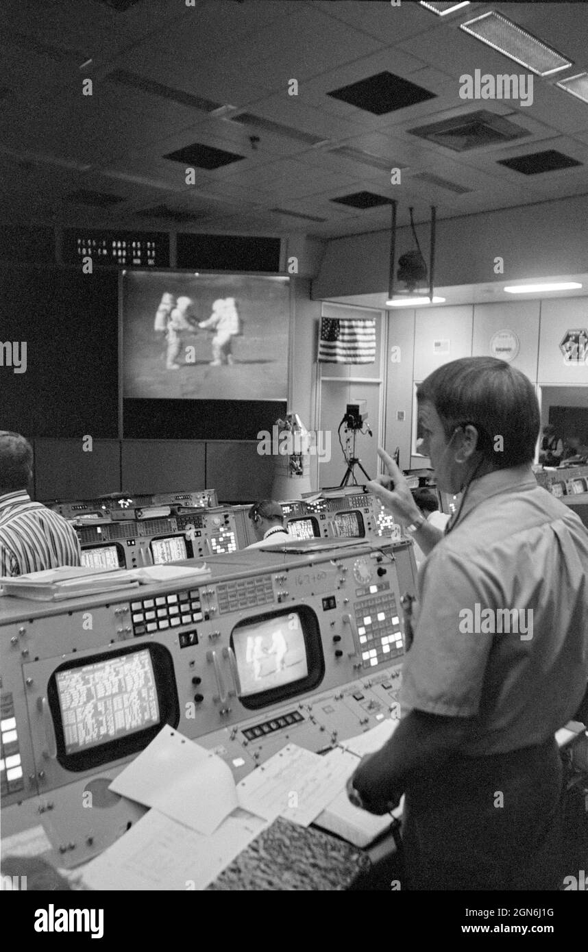 (2. August 1971) --- Gerald D. Griffin, im Vordergrund, steht während der dritten extravehiculären Aktivität (EVA) von Apollo 15 auf der Mondoberfläche in der Nähe seiner Konsole im Mission Operations Control Room (MOCR). Griffin ist Flugdirektor des Gold Team (Schicht 1) für die Apollo 15-Mission. Die Astronauten David R. Scott und James B. Irwin sind auf der großen Leinwand an der Vorderseite des MOCR zu sehen, während sie an der Probenahme auf der Mondoberfläche teilnehmen. Stockfoto