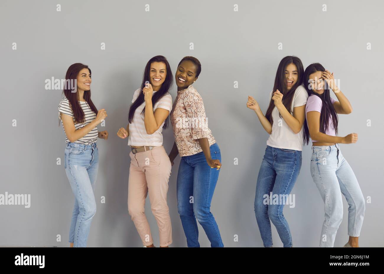 Gruppe von schönen jungen multinationalen Freundinnen, die glücklich tanzen und Spaß zusammen haben. Stockfoto