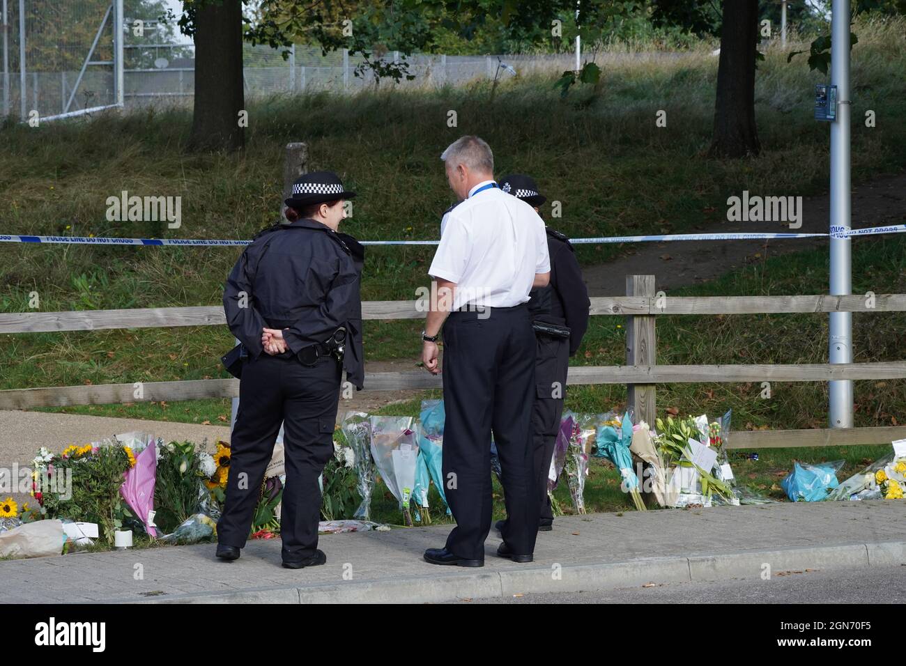 Polizeibeamte durch Blumengebete im Cator Park in Kidbrooke, im Süden Londons, in der Nähe des Fundort der Leiche von Sabina Nessa. Beamte, die die Tötung der 28-jährigen Lehrerin untersuchten, sagten, dass sie ihr Haus auf der Astell Road verlassen und am vergangenen Freitag durch den Cator Park in Richtung Depot-Bar auf dem Pegler Square im Dorf Kidbrooke gegangen war, als sie angegriffen wurde. Bilddatum: Donnerstag, 23. September 2021. Stockfoto