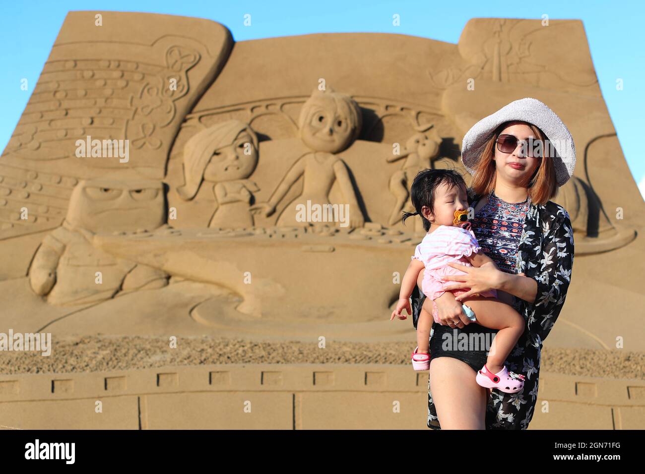 Fulong, New Taipei, Taiwan. September 2021. Eine Mutter und ihre Tochter, die für ein Foto mit Sandskulpturen posiert, sind am Fulong Beach in New Taipei während des Fulong International Sand Sculpture Art Festival 2021 inmitten der Covid-19 Pandemie zu sehen. Die Künstler des Festivals demonstrieren Taiwan und die Berge der Welt und zeigen Fahrradtouren auf dem goldenen Sandstrand von Fulong Beach. (Bild: © Daniel Ceng Shou-Yi/ZUMA Press Wire) Bild: ZUMA Press, Inc./Alamy Live News Stockfoto
