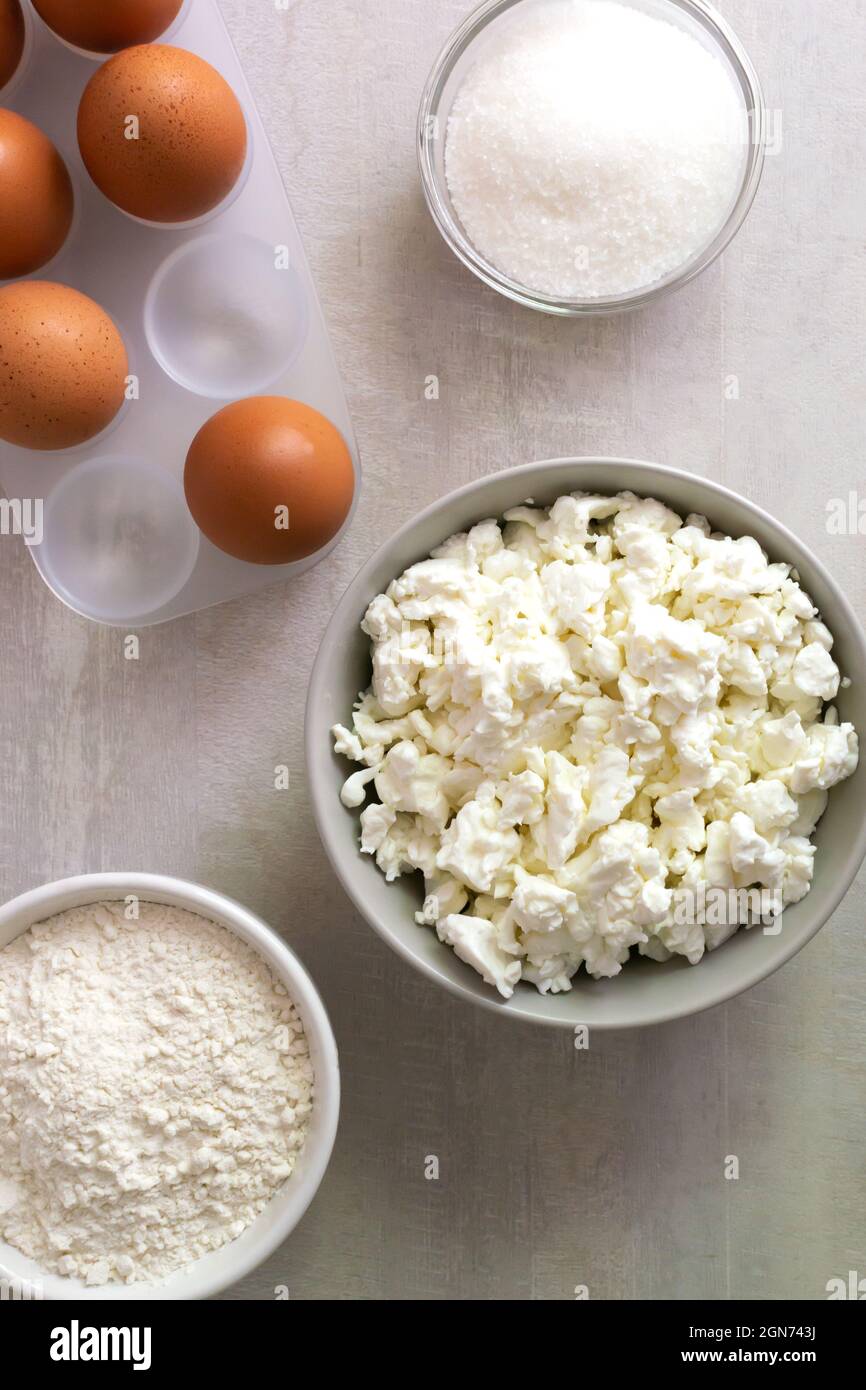 Eine Reihe von Zutaten für die Herstellung von Muffins: Quark, Eier, Zucker, Mehl. Gesundes Ernährungskonzept. Vertikale Ausrichtung. Draufsicht. Stockfoto