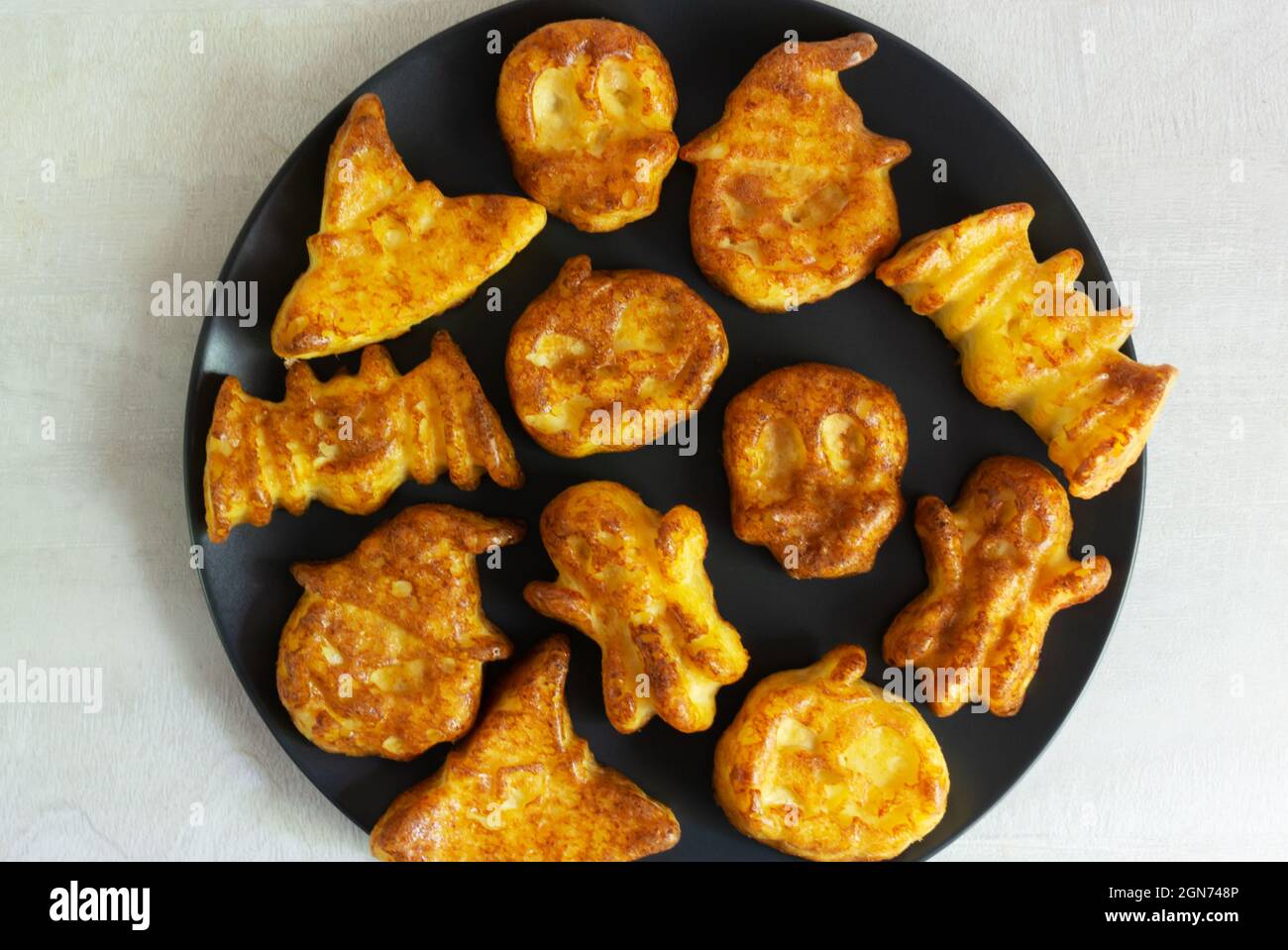 Schritt-für-Schritt Zubereitung von Hüttenkäse-Muffins für Halloween. Süße Cupcakes mit Monstern für Kinder auf einem schwarzen Teller. Draufsicht. Backen im Stockfoto