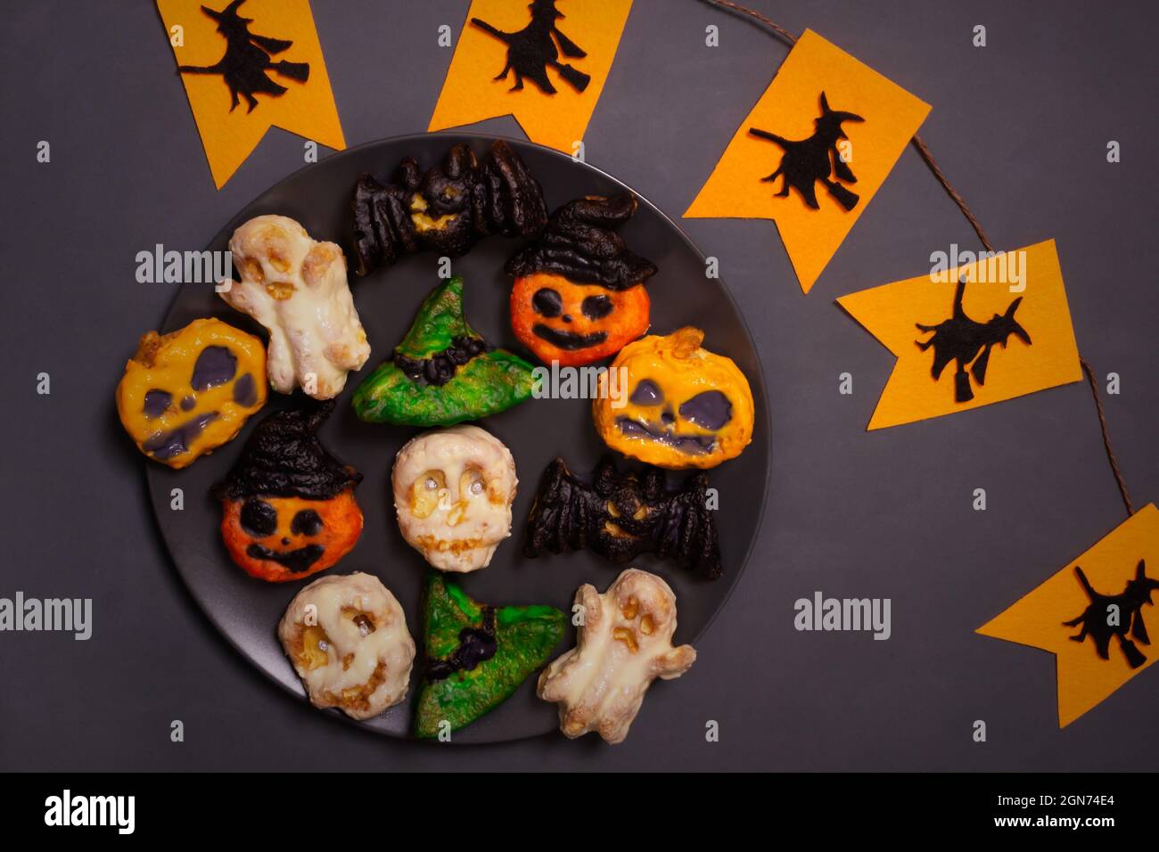 Schritt-für-Schritt Zubereitung von Hüttenkäse-Muffins für Halloween. Süße Cupcakes mit Monstern für Kinder auf einem schwarzen Teller mit Girlande. Farbiger p Stockfoto