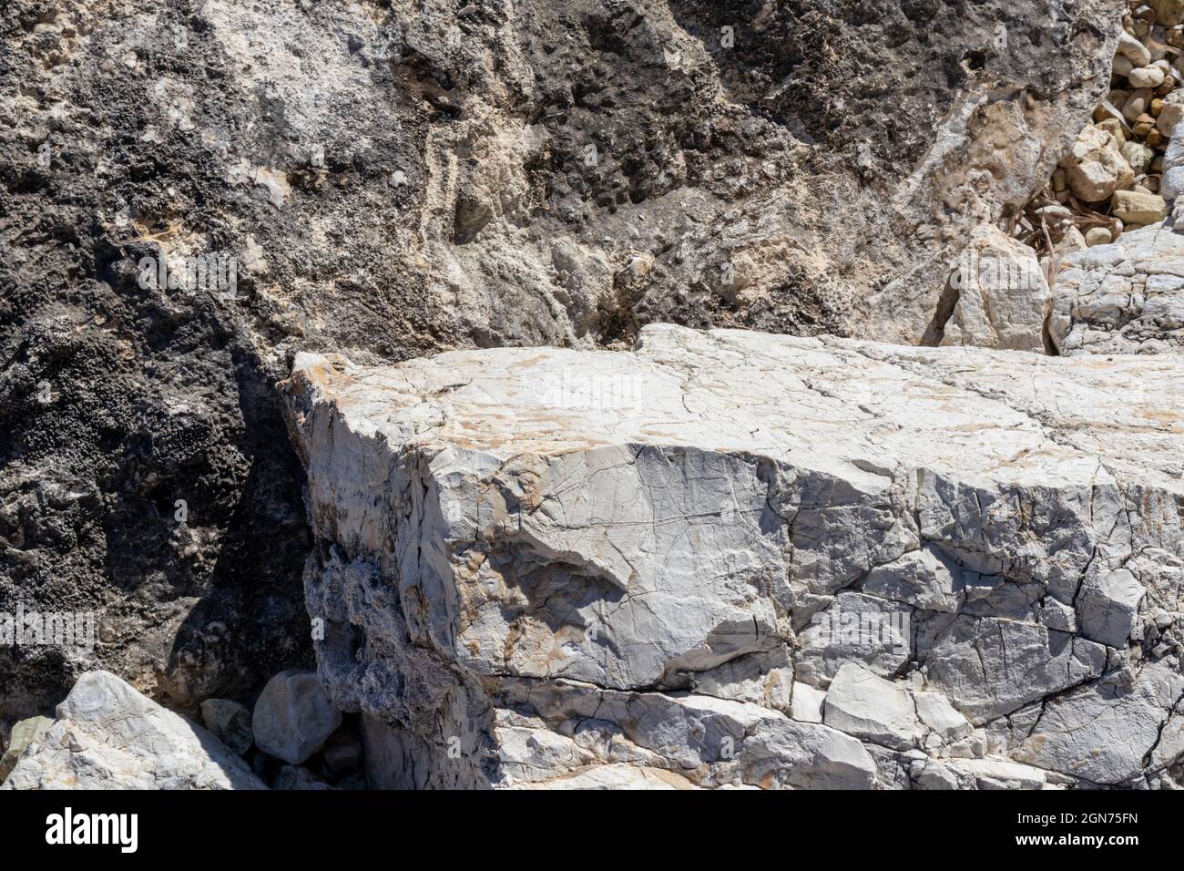 Nahaufnahme aus weißem, großem Marmorgestein mit scharfer Textur. Leichte Steinoberfläche Musterdetails im sonnigen Griechenland Stockfoto