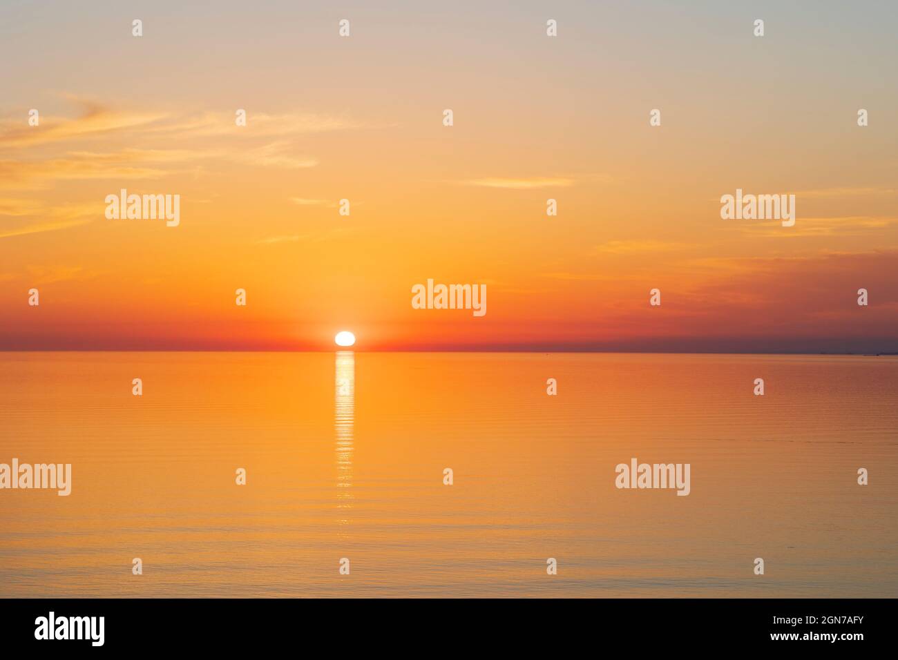 Die Sonne geht bei Sonnenuntergang über einem ruhigen Meer unter Stockfoto