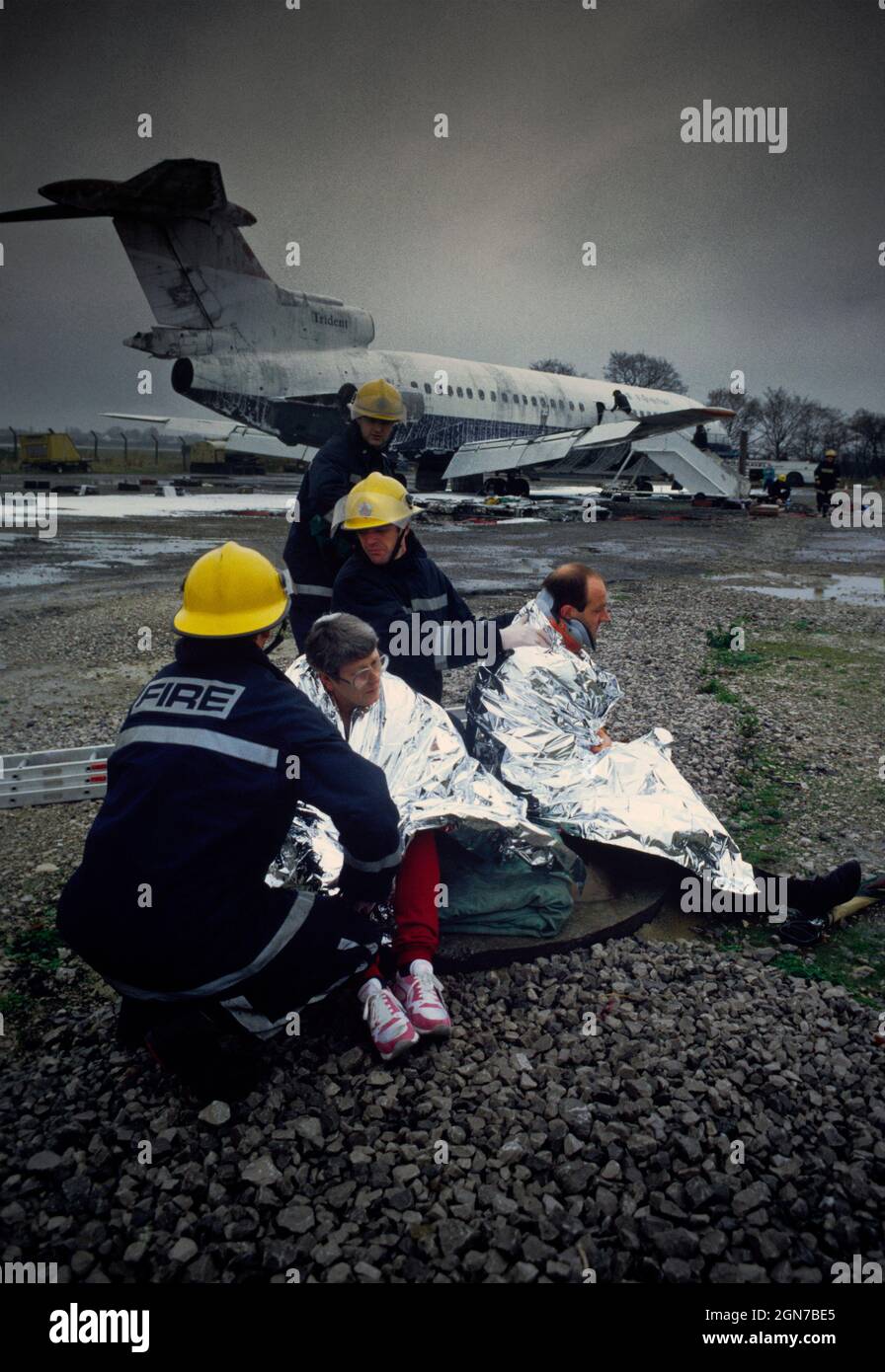 Feuerwehrleute und Sanitäter, die während einer Schulung und Koordinationsübung am Flughafen Manchester Freiwillige mit simulierten Verletzungen besuchen. Stockfoto