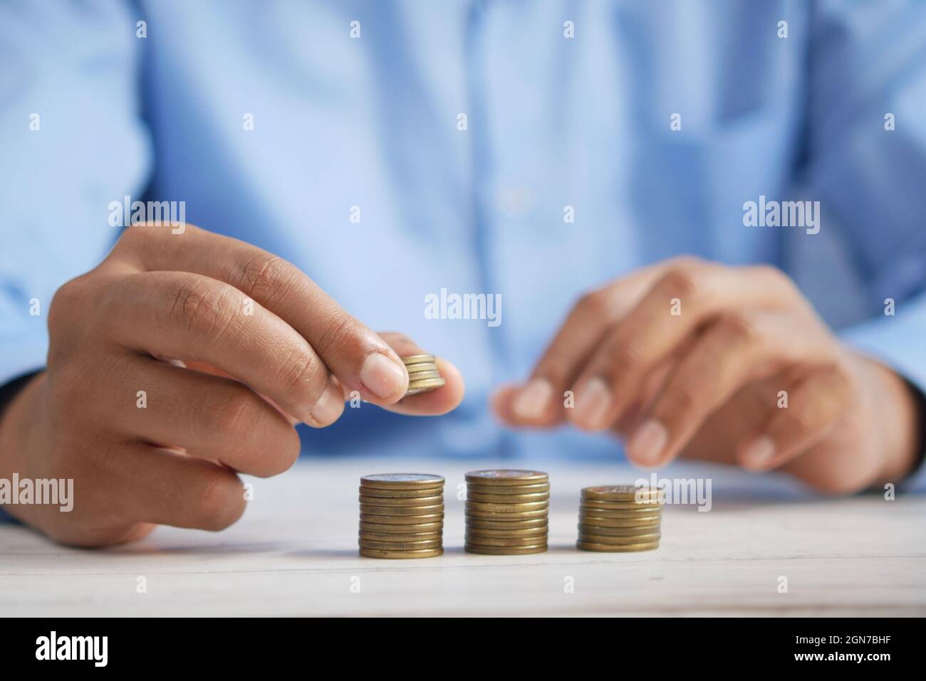 Man's Hand Putting Stapel von Münzen Stockfoto