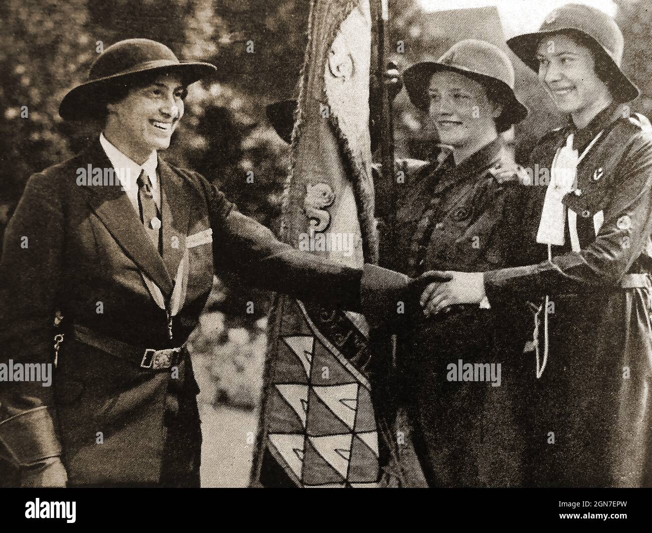 Ein Foto aus den 1930er Jahren von Lady Baden Powell (links), die sich mit Farbsträgern die Hände schüttelt (mit dem Standard der Chefarzter) in Torquqy, Großbritannien. Stockfoto