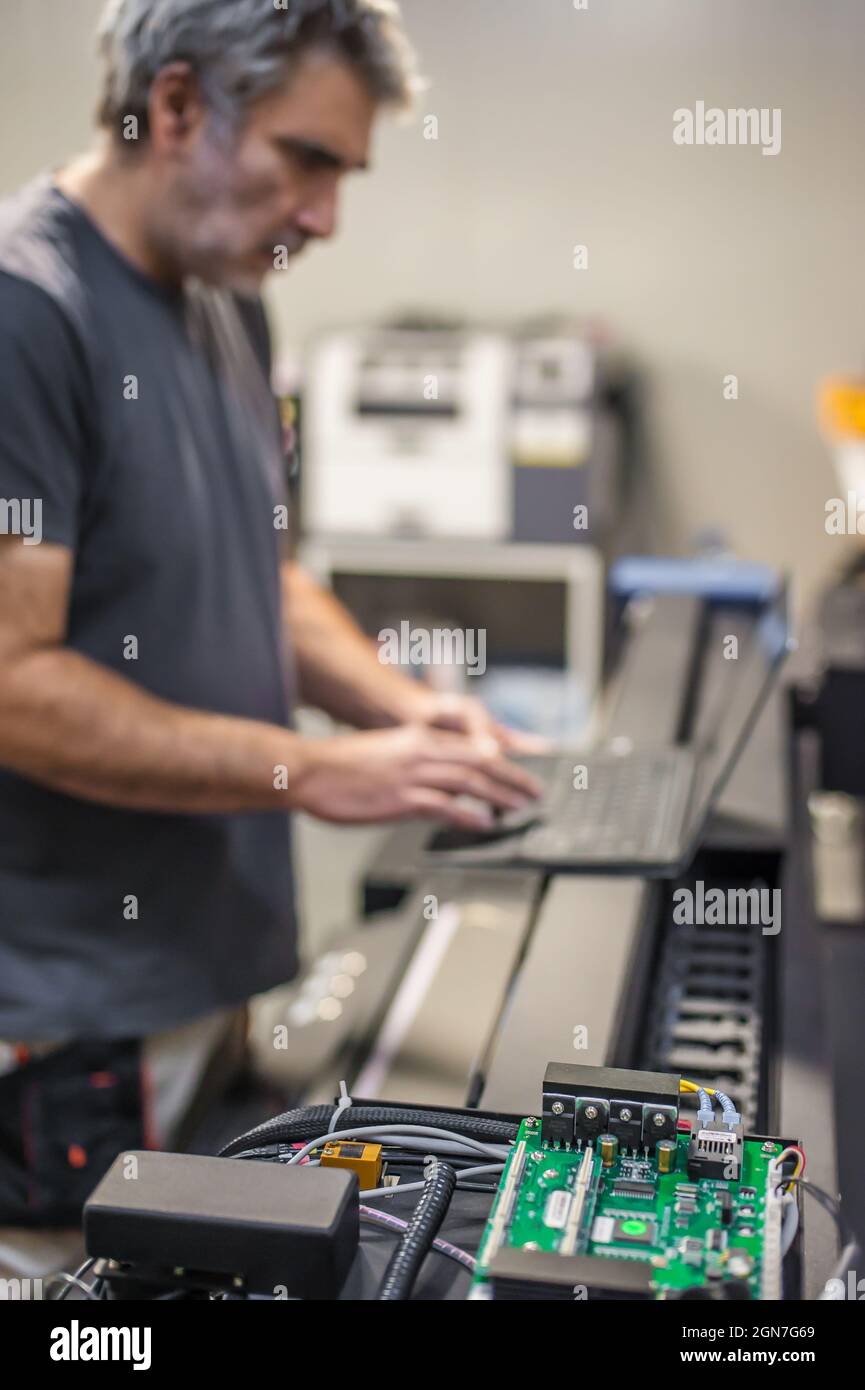 Servicetechniker im Außendienst, Elektriker, inspizieren und steuern die Hardware- und Softwaresysteme der Maschine mit einem Laptop. Elektroinst Stockfoto