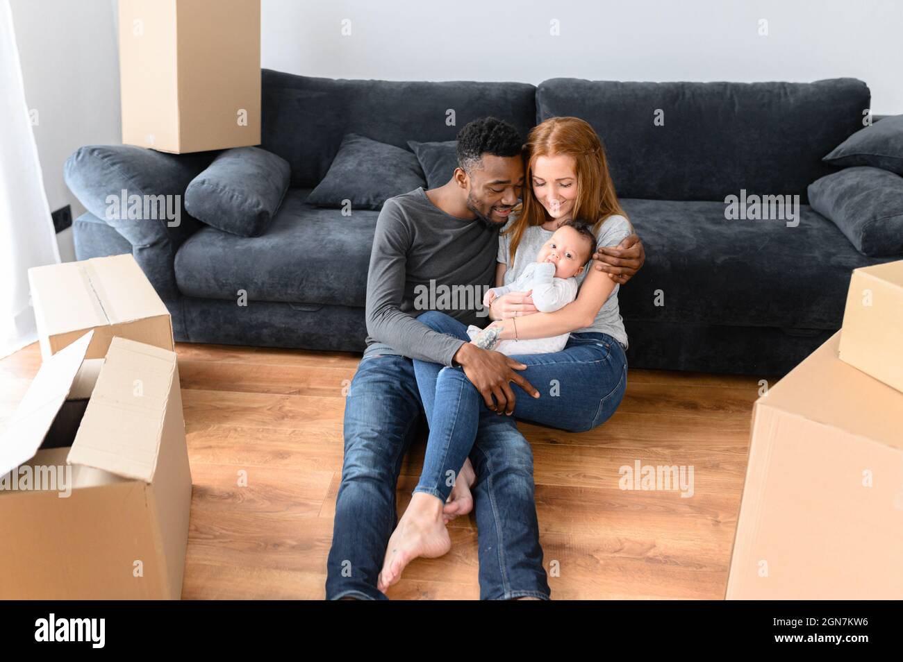 Glückliche Mixed-Race-internationale Familie während des Auspackens Tag, Umzug in das neue Zuhause. Afrikanischer Vater, kaukasische Mutter und niedliche Biracial Baby-Tochter liegen auf dem Boden zwischen Pappkartons Stockfoto Glückliche Mixed-Race-internationale Familie während des Auspackens Tag, Umzug in das neue Zuhause. Afrikanischer Vater, kaukasische Mutter und niedliche Biracial Baby-Tochter liegen auf dem Boden zwischen Pappkartons Stockfoto
