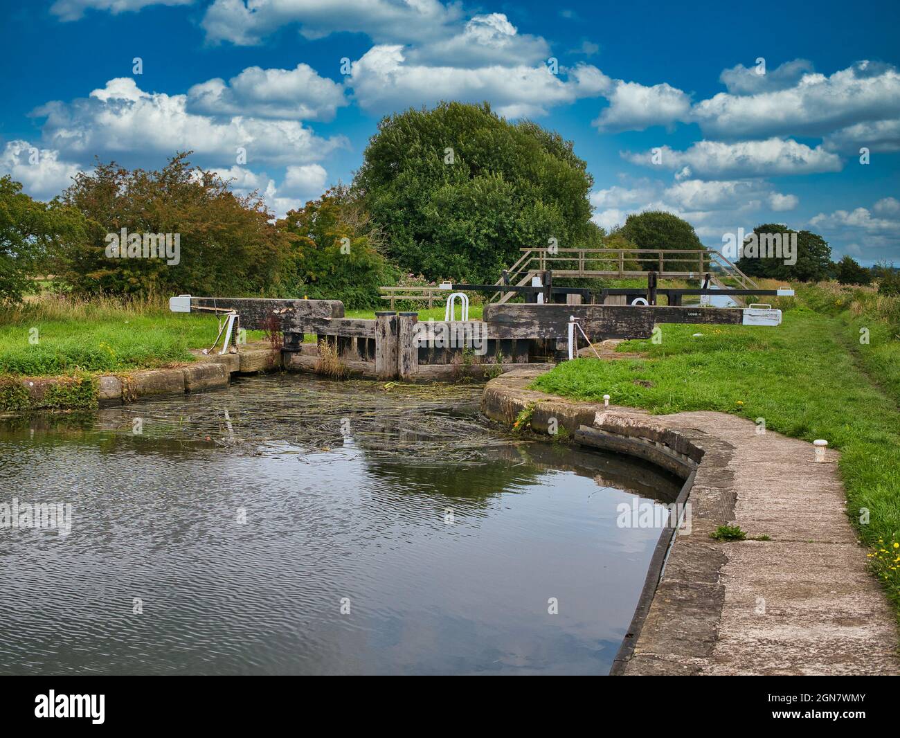 Moss Lock (4) und eine Fußgängerbrücke am Rufford Branch des Leeds Liverpool Canal in Lancashire, Großbritannien. Aufgenommen an einem sonnigen Tag im Sommer. Stockfoto