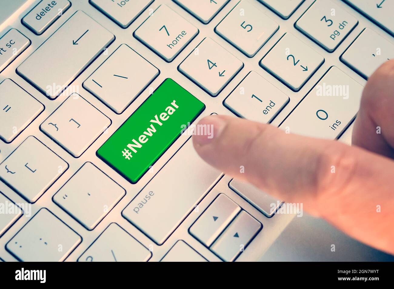 Nahaufnahme des Fingers auf der Tastatur mit dem Wort „NEUJAHR“. Ein männlicher Finger drückt eine Farbtaste auf einer grau-silbernen Tastatur eines modernen Laptops. Taste wi Stockfoto