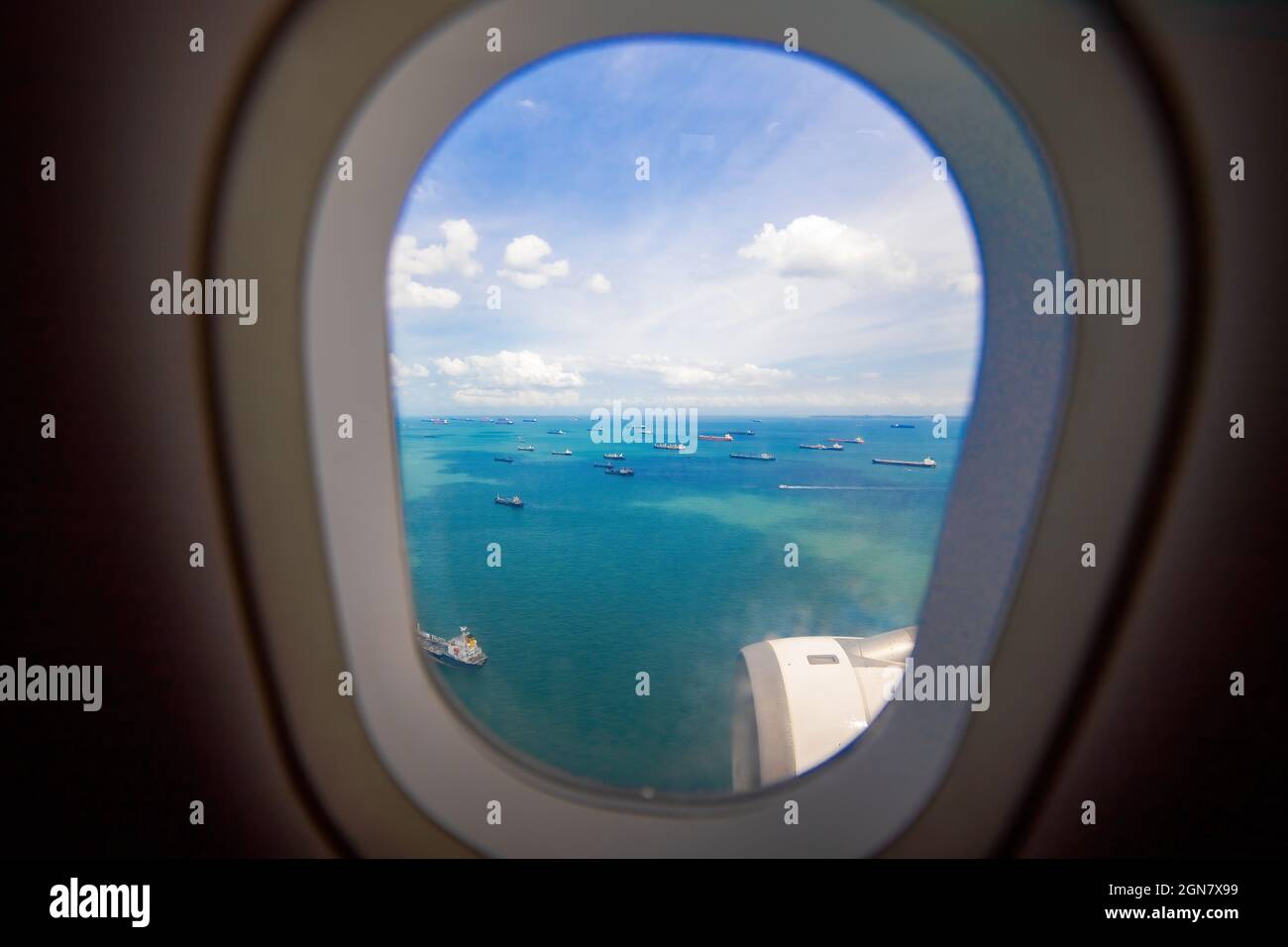 Schöne Aussicht vom Fenster des Flugzeugs auf das Meer und Frachtschiffe. Unbeschwerte Aussicht vom Bullauge Landungsflugzeug Stockfoto