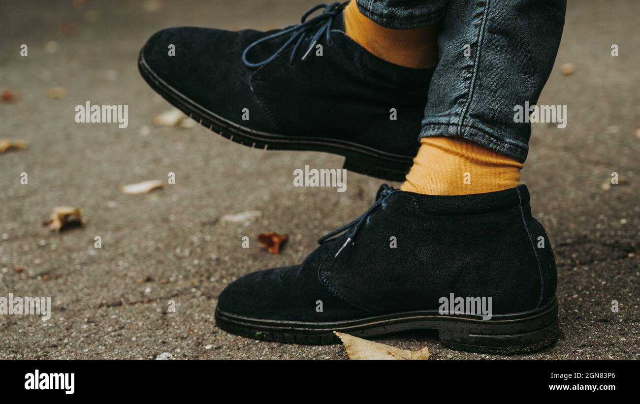 Nahaufnahme der Beine in blauen Wildlederschuhen und gelben Socken. Herbstmode für Männer. Stockfoto