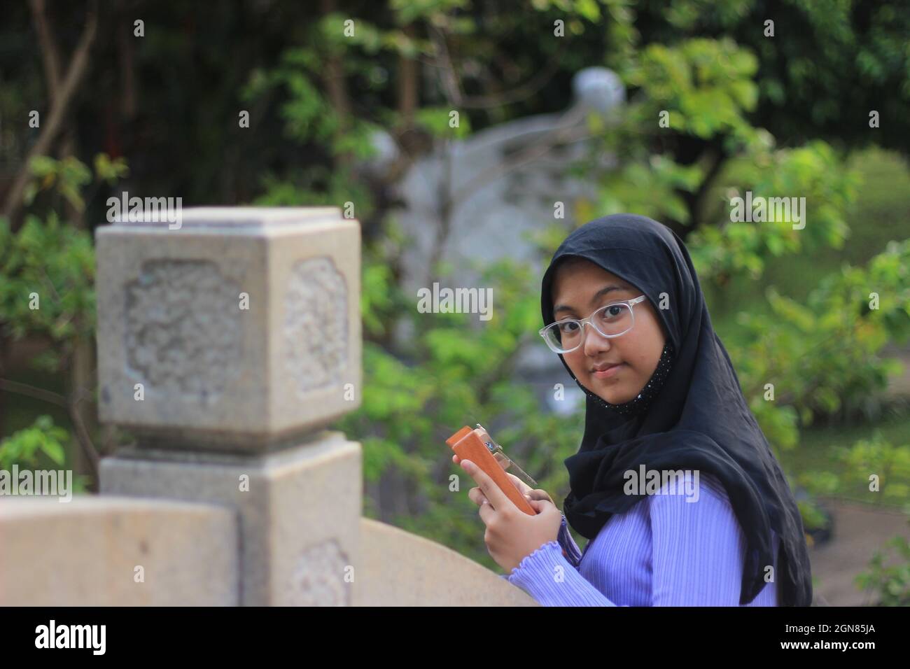 Mit Blick auf Camera Standing Muslimah oder Islam Girl Hold Kalimba, ein akustisches Musikinstrument aus afrika Stockfoto