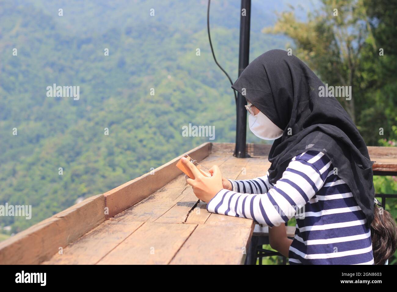 Indonesia Muslimah oder Islam Girl Hold Kalimba, ein akustisches Musikinstrument aus afrika mit Pancar Mountain als Hintergrund Stockfoto