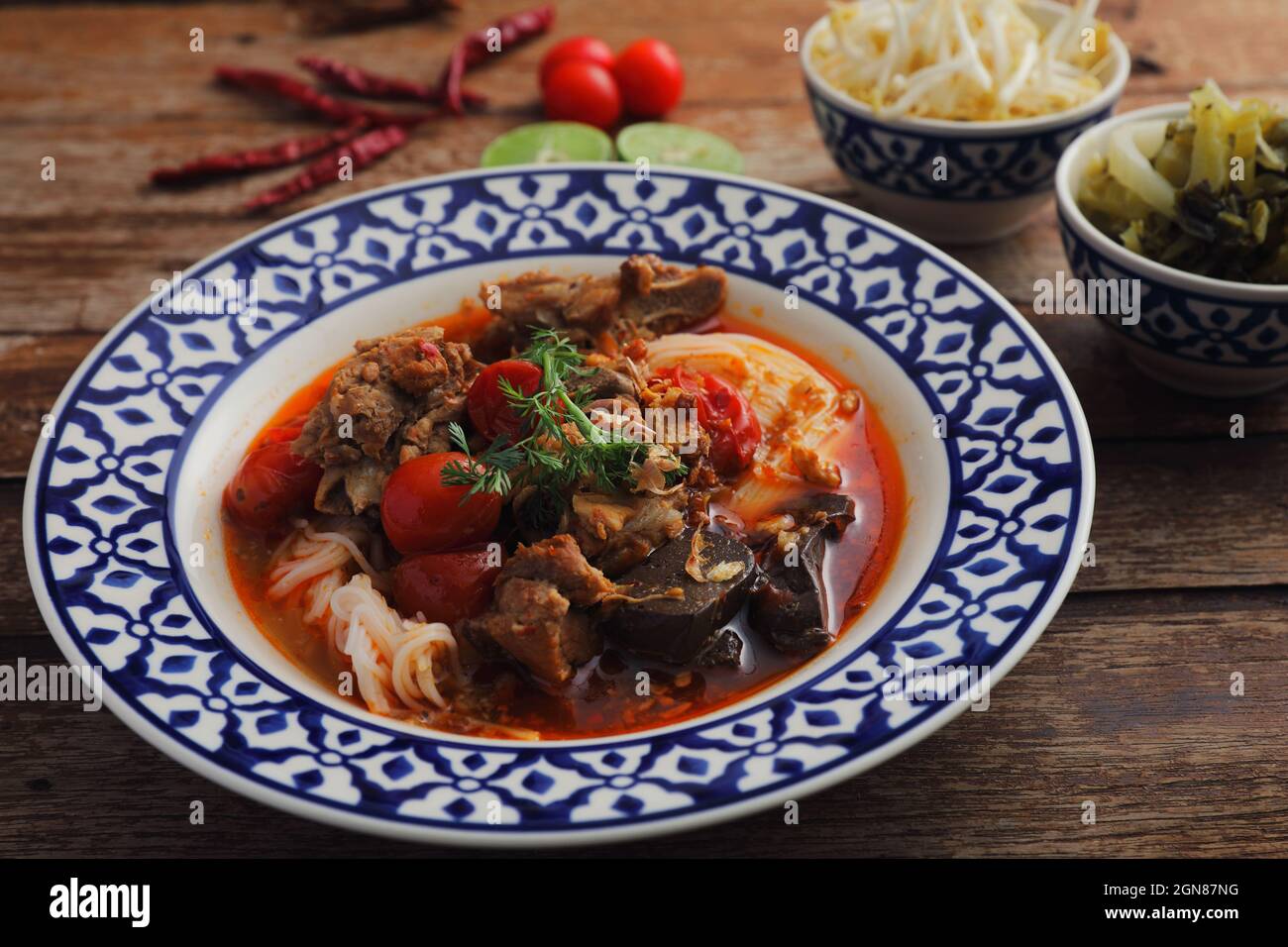 Lokale nordthailändische Küche Reisnudeln mit Schweinefleisch in würzigen Suppe im Holzhintergrund Stockfoto