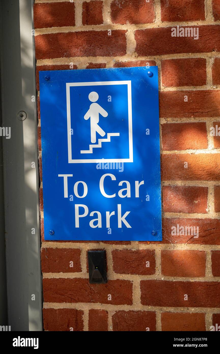 Blaues Schild an der Wand, auf dem die Stufen zum Parkplatz auf einer Ziegelmauer unter dem strahlend hellen Sonnenlicht stehen Stockfoto