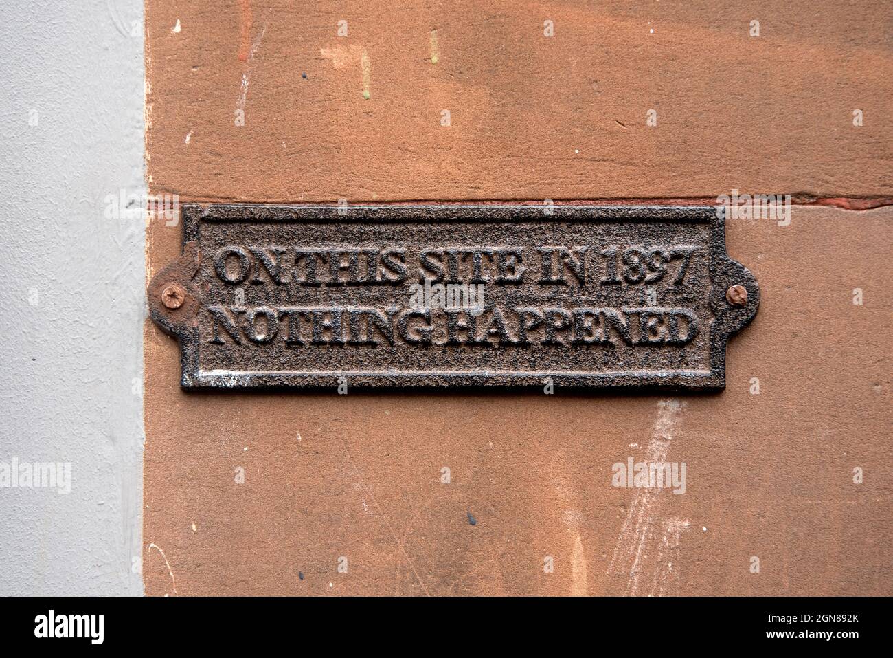 Metallanmerkung an der Wand mit der Aufschrift: „auf dieser Website im Jahr 1897 ist nichts passiert“. Stockfoto