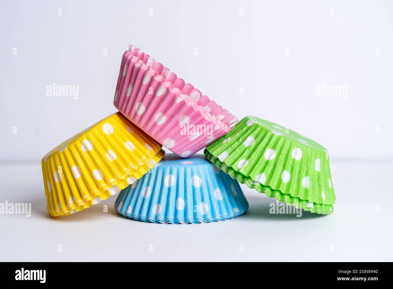 Vier Packungen fettfester Pappbecher (Feen)-Kuchenhüllen in leuchtenden Farben für die Präsentation auf Partys und Veranstaltungen nach dem Backen im Ofen rosa, grün, Stockfoto