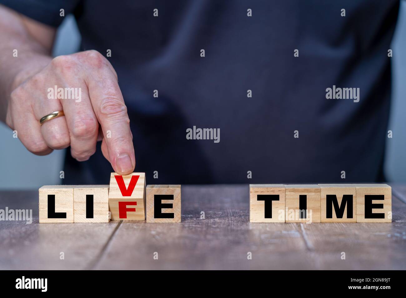 Holzwürfel Abstract in A Life oder Live Time Mans Hand dreht einen Holzblock und ändert die Worte Live to Life Stockfoto