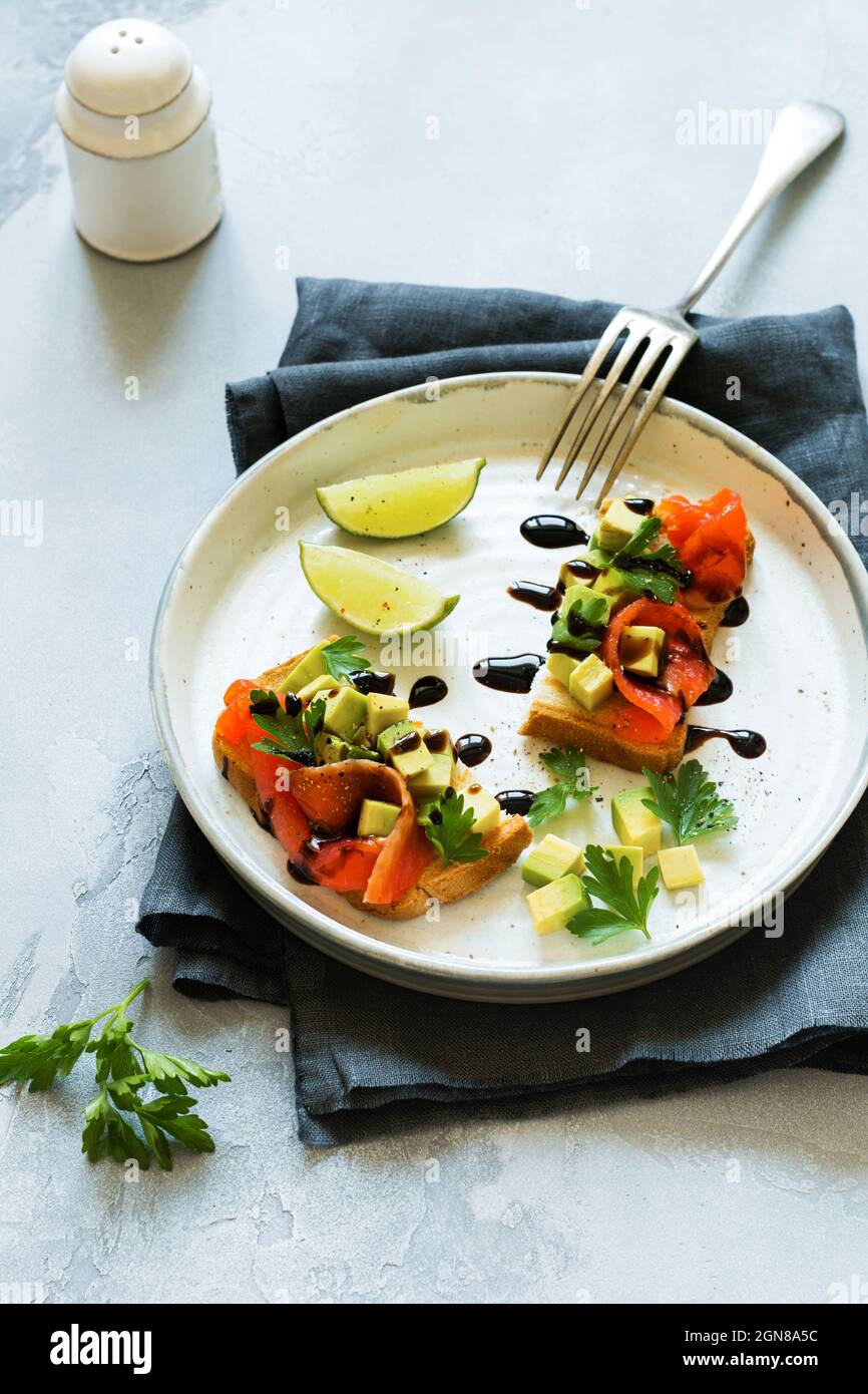 Avocado- und Lachsbrote mit Balsamico-Sauce und Koriander auf altem Olivenbrett. Draufsicht Stockfoto