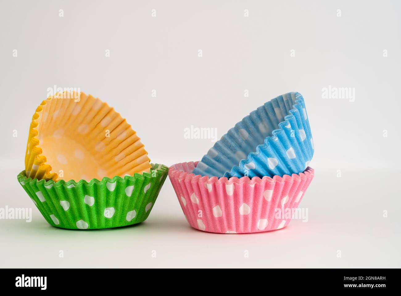 Vier Packungen fettfester Pappbecher (Feen)-Kuchenhüllen in leuchtenden Farben zur Präsentation auf Partys und Veranstaltungen nach dem Backen im Ofen Stockfoto