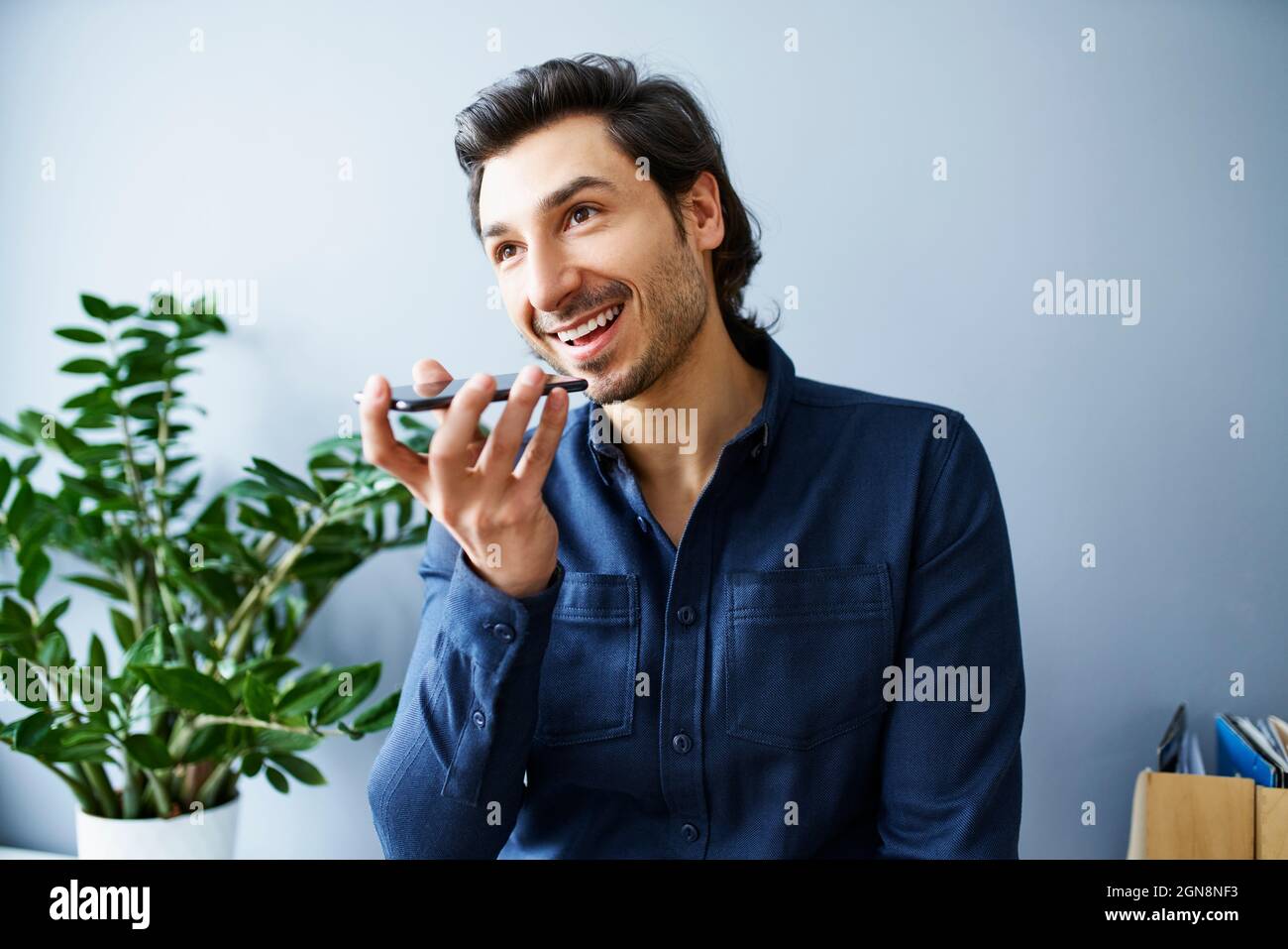 Geschäftsmann, der im Büro Voicemail auf dem Smartphone sendet Stockfoto