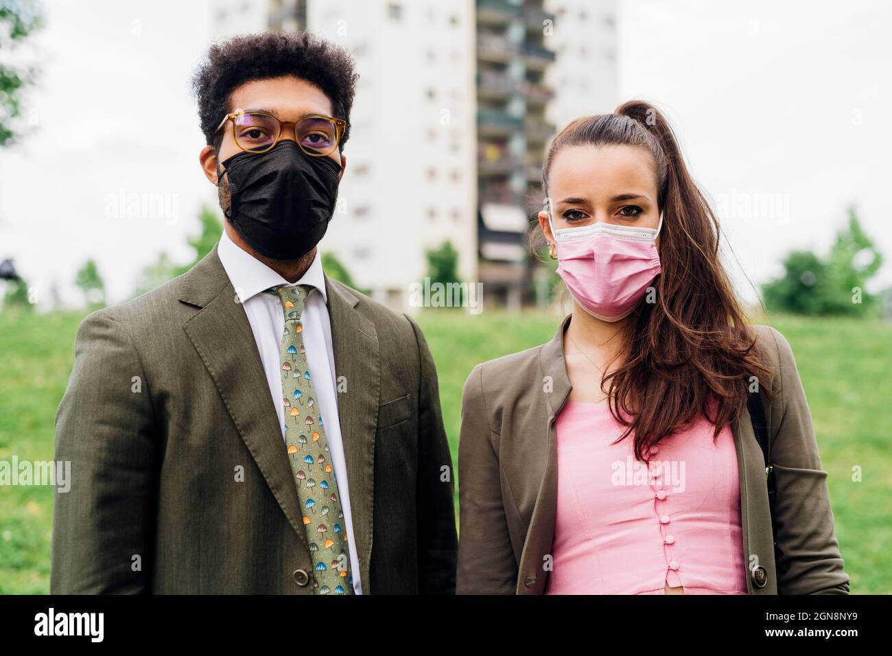 Business-Profis mit schützenden Gesichtsmasken im Park Stockfoto