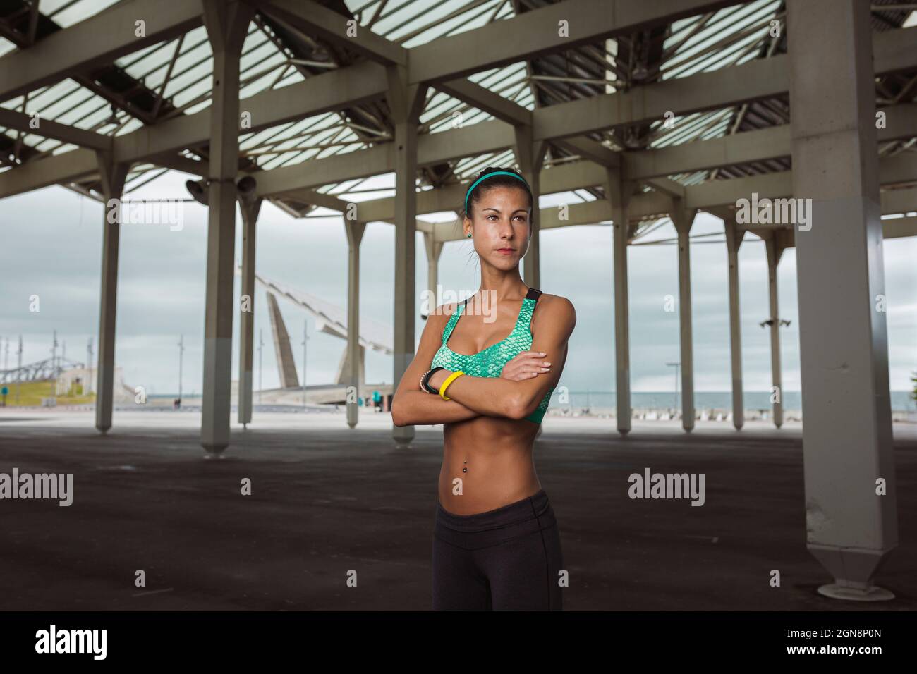 Sportlerin mit gekreuzten Armen, die auf dem Fußweg steht Stockfoto